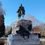 Bronze equestrian statue of General Martínez-Campos on a tiered stone pedestal reflected in a pool.