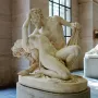 Satyre et bacchante marble sculpture showing two intertwined figures in a museum hall