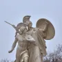 Athena Protects the Young Hero stone sculpture showing a helmeted goddess with shield and spear behind a young hero.