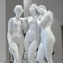 The Three Graces, a white marble sculpture of three female figures in a museum gallery.