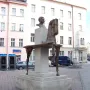 Bronze sculpture of Jaroslav Hašek with a fragmented horse on a multi-tiered stone pedestal in a paved square.