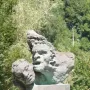 War Memorial of Capoulet-et-Junac with a weathered stone cluster of anguished faces on a concrete pedestal.