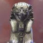 Thutmose III sphinx figurine in profile with gold inlays on a dark background