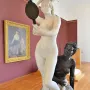 Le Miroir sculpture showing a white marble nude woman holding a hand mirror above a kneeling bronze figure on a decorative base.