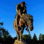 End of the Trail bronze sculpture showing a slumped rider on a lowered horse atop a stone base.
