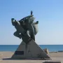 Monument of Eupatoria Assault bronze sculpture with three figures on a stone base by the sea.