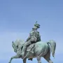 Victor Emmanuel II equestrian statue in bronze atop a stone pedestal against a blue sky.