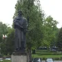 Mickiewicz Monument, a dark statue of a bearded man holding a book on a tall stone pedestal in a park.