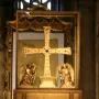 The Cross of the Angels, a jeweled golden cross displayed in a glass case with kneeling angel figures beside it.