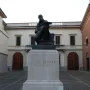 Bronze monument to Mose Bianchi showing a seated bearded man holding a painter\'s palette on a stone pedestal.