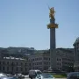 The Freedom Monument with a golden equestrian statue atop a tall column in a city square.