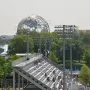 The Unisphere rises above trees and stadium stands under a hazy sky.
