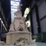 Fons Americanus by Kara Walker, a large white tiered fountain with sculpted figures and sea creatures inside a vast industrial hall.