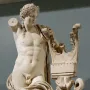 Apollo of Cyrene marble statue leaning on a carved column with a coiled snake, missing its right arm