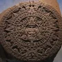 The Aztec Sun Stone carved as a large circular stone disc with a central face and concentric rings of symbols.