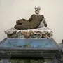 Babuino Fountain with a reclining stone figure over a rectangular basin of greenish water.