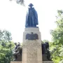 Von Steuben monument with a dark statue atop a stone pedestal, flanked by bronze figures and carved inscriptions.