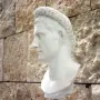 Bust of Augustus wearing a gemmed crown, shown in profile against a stone wall.