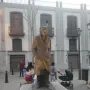 Bronze statue of César Vallejo on a stone pedestal in a paved square.