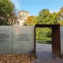 Entrance to the Memorial to the Murdered Sinti and Roma of Europe, with a dark archway and panels of text beside a circular water basin.
