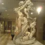 Marble sculpture of A Faun Teased by Children showing a nude faun with children playing around him and holding grapes overhead.