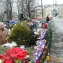 Solovetsky Stone covered with floral wreaths and bouquets as people gather around the memorial.