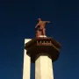 Vulcan statue atop a tall concrete pedestal against a dark blue sky.
