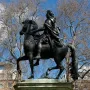 William III equestrian statue on a tall pedestal in a green park, with buildings in the background.