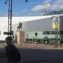 Marshal Mannerheim equestrian statue in front of a modern glass building in Helsinki, with a pedestrian in the foreground.