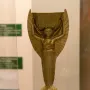 Jules Rimet Trophy with a winged female figure holding a laurel wreath above a spherical FIFA base.