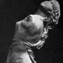 Partial stone sculpture of the Dancing Maenad shown in profile, with arched back and long hair swept backward.