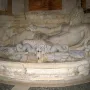 Marforio, a reclining stone male figure with water flowing from a beast-head spout into a basin.