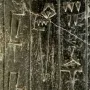 Close-up of the Iddi-Ilum statuette showing deeply carved cuneiform script on a weathered stone surface.