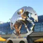 Rolling Horse sculpture in front of a modern glass building under a clear blue sky.