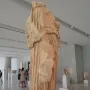 Procne and Itys marble sculpture in a museum gallery, with draped folds and missing upper sections.