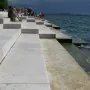 Concrete steps of the Sea Organ descending into a dark, choppy sea, with people seated on the upper levels.