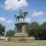 Victor Emmanuel II equestrian statue in bronze atop a stone pedestal against a blue sky.