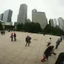 Cloud Gate reflects Chicago skyscrapers, trees, and people in the plaza.