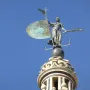 The Giraldillo sculpture of a robed woman holding a shield and palm frond against a blue sky.