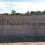 Graffiti on a stone wall at the Holocaust Memorial, with trees and streetlights visible above it.