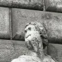 Pasquino, a severely weathered stone statue with a missing left arm, shown against rough stone blocks.