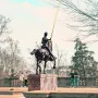 Joan of Arc equestrian statue with a raised yellow lance in a park setting