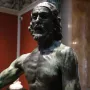 Bronze bust of Saint John the Baptist with long hair and a beard, showing a dark greenish patina.