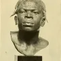 Dark bust of an Aruwimi Native with raised patterns on the forehead and scalp, mounted on a simple pedestal.