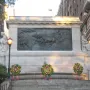 Firemen\'s Memorial with a stone relief of horses pulling a wagon, flanked by statues and wreaths.