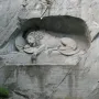 The Lion Monument in Luzern showing a wounded lion carved into a rock grotto with a shield and broken spear.