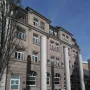 Tall white pillars of the Way of Human Rights stand in front of a stone building with many windows.
