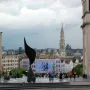 The Whirling Ear sculpture in a circular fountain in a public plaza, with a city spire in the background.