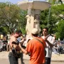 Dupont Circle Fountain with water flowing from the upper bowl and people gathered around it, including musicians in the foreground.