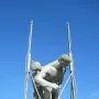 Sztafeta sculpture showing two nude male figures against a blue sky, with metal supports around the figures.